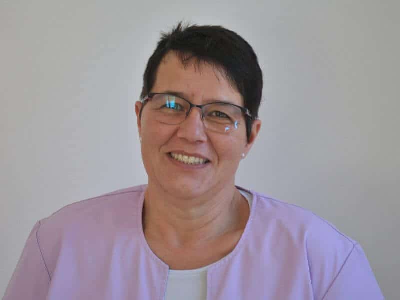 Portraitfoto von Dunja Hartmann, Mitarbeiterin der Hausarztpraxis Neumünden in Hann. Münden. Sie trägt eine helle Kasack-Jacke, lächelt freundlich in die Kamera und trägt eine Brille. Frau Hartmann ist zuständig für Laboruntersuchungen und diagnostische Tätigkeiten in der Praxis.